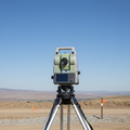 Modern total station instrument mounted on a tripod on a survey site, clear sky background
