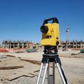 Automatic optical survey level mounted on an aluminum tripod on a construction site, clear sky