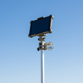 Rugged tablet mounted on a bracket atop a prism pole against a clear sky
